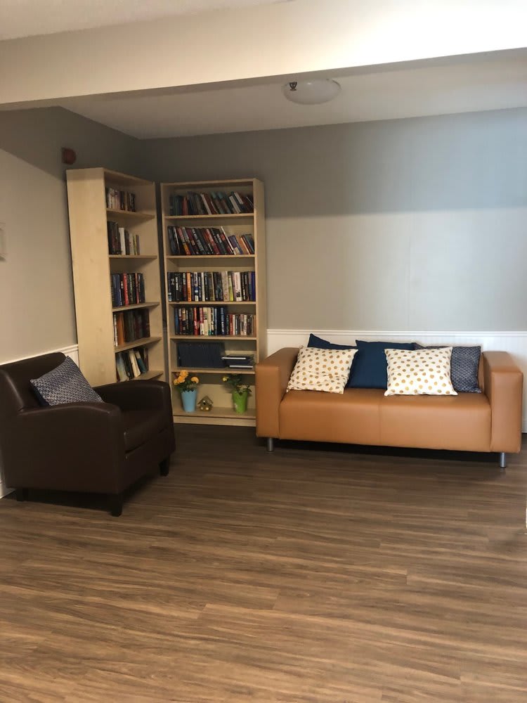 A cozy living room with a sofa, bookshelf, and armchair on a hardwood floor.