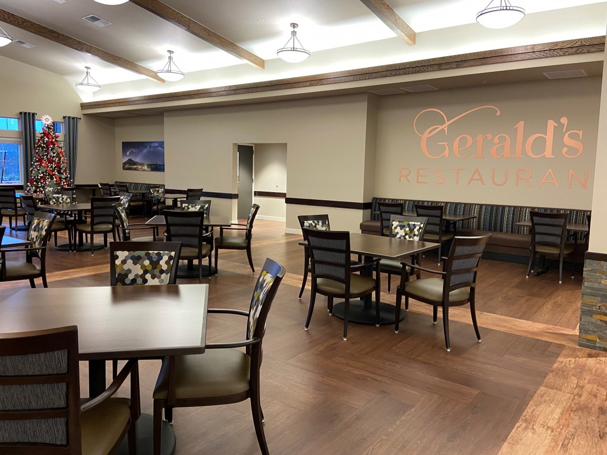 A spacious dining area with neatly arranged tables and chairs under modern lighting.