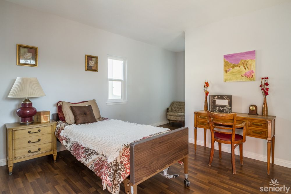 A cozy bedroom with a single bed and a small desk in the corner.