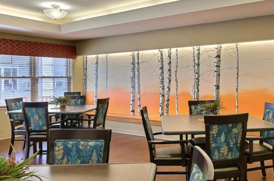 A modern dining area with tables and chairs, featuring an artistic wall mural of birch trees.