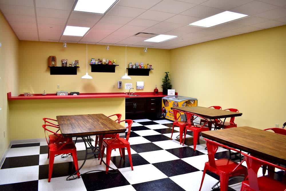 A retro-style diner with checkered flooring, red chairs, and yellow walls.