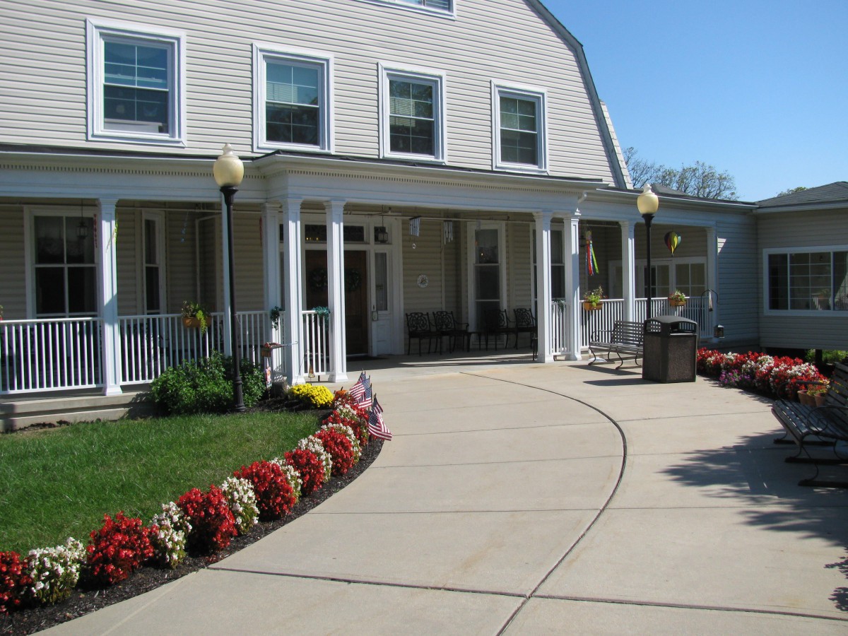 A house with a landscaped pathway lined with flowers leading to a porch.