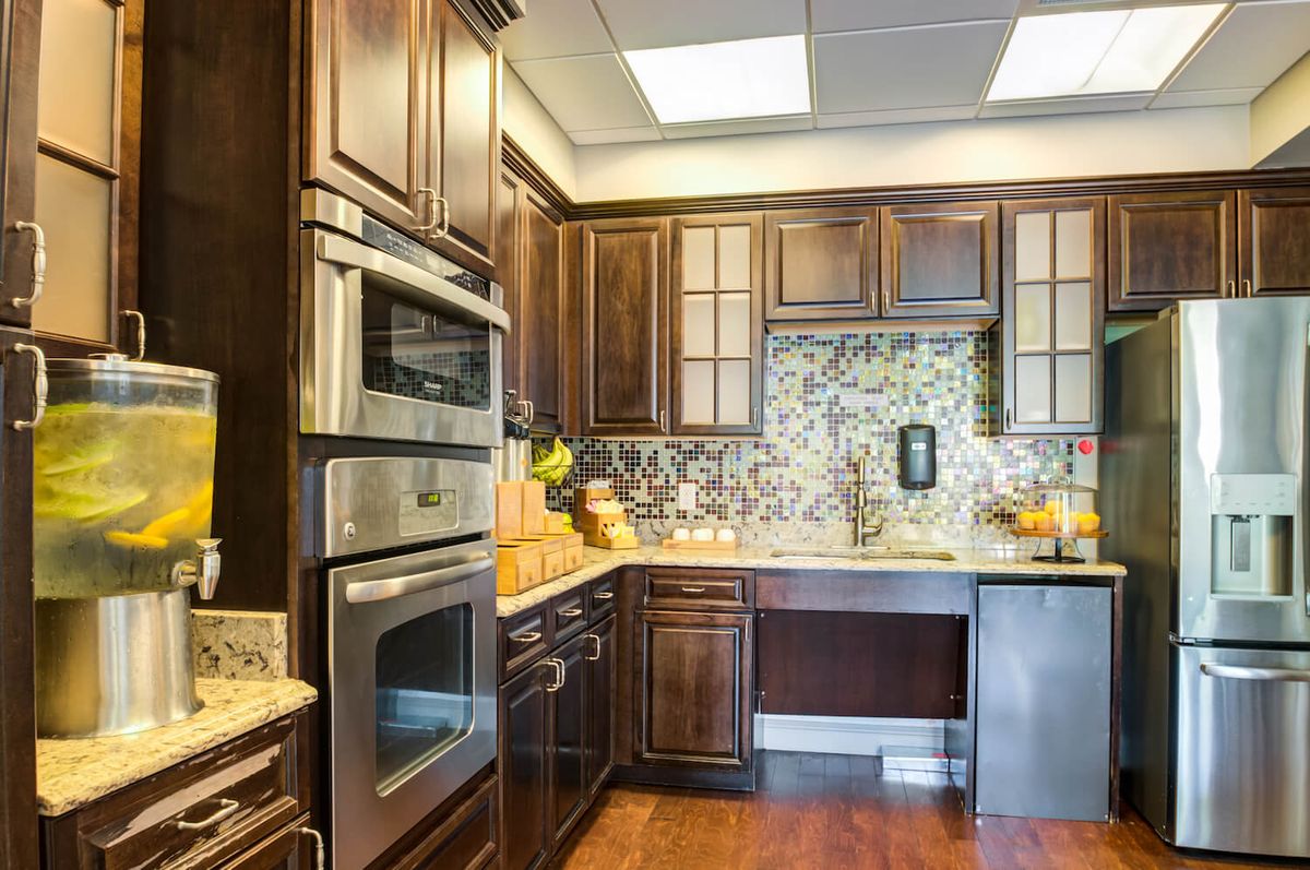 A modern kitchen with dark wood cabinets, stainless steel appliances, and a decorative backsplash.