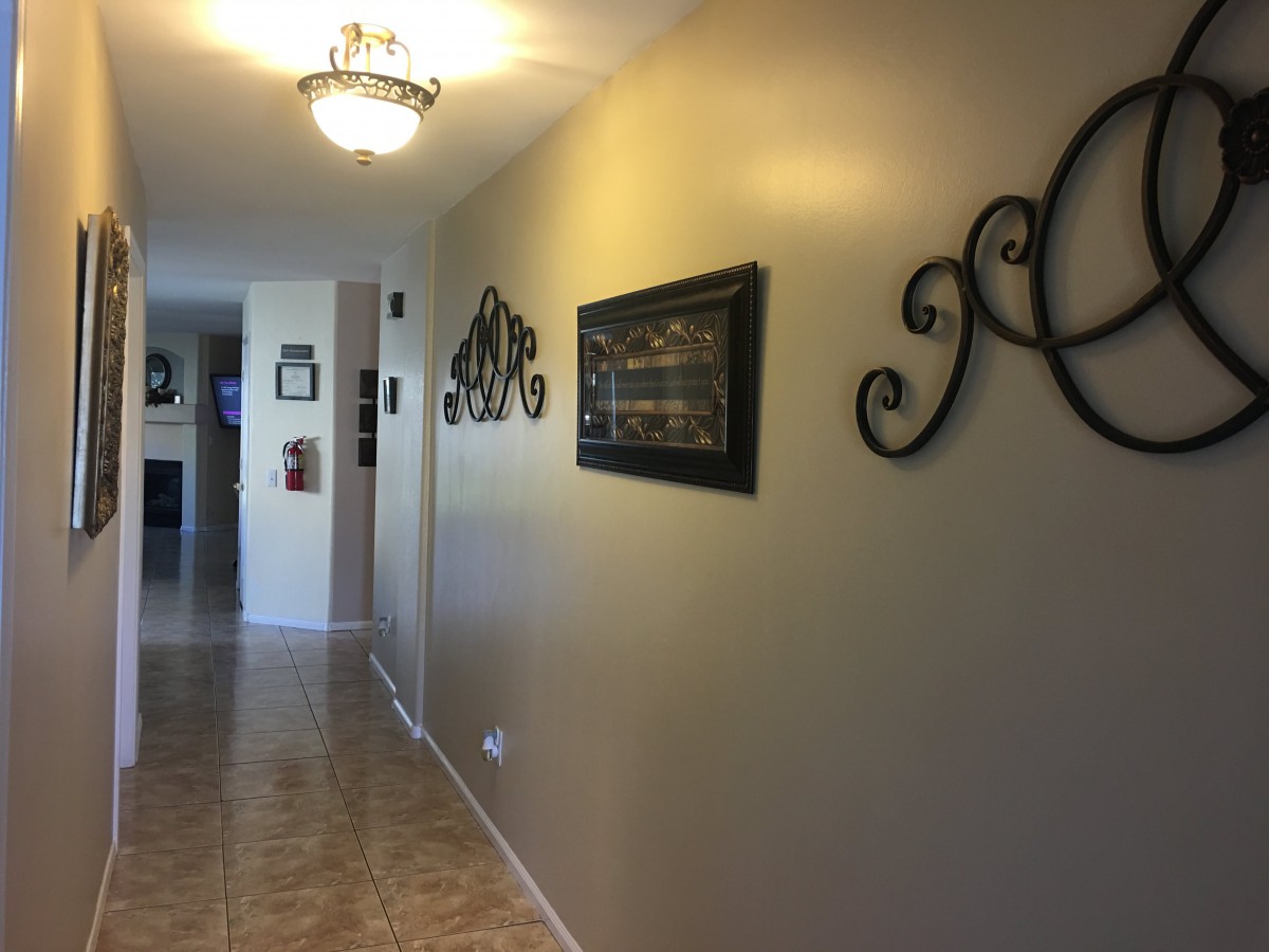 A well-lit hallway featuring decorative wall art and tiled flooring.