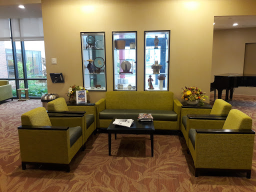 A cozy and inviting waiting area featuring green sofas, a coffee table, and decorative plants.