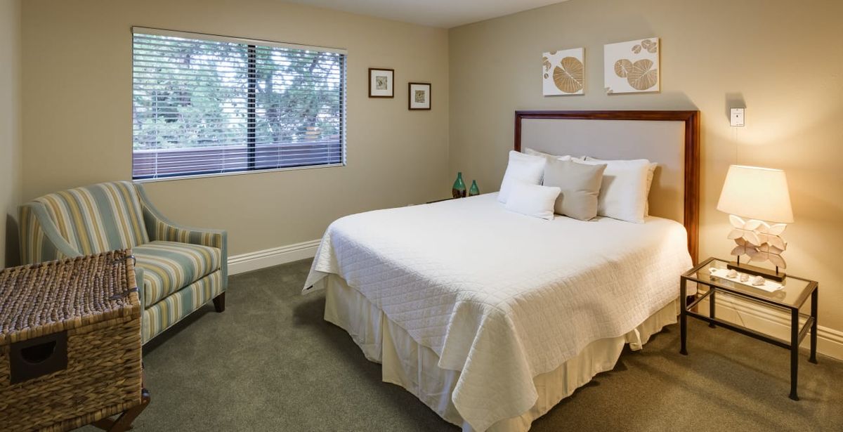 A minimalist bedroom with a neatly made bed and framed artwork on the walls.