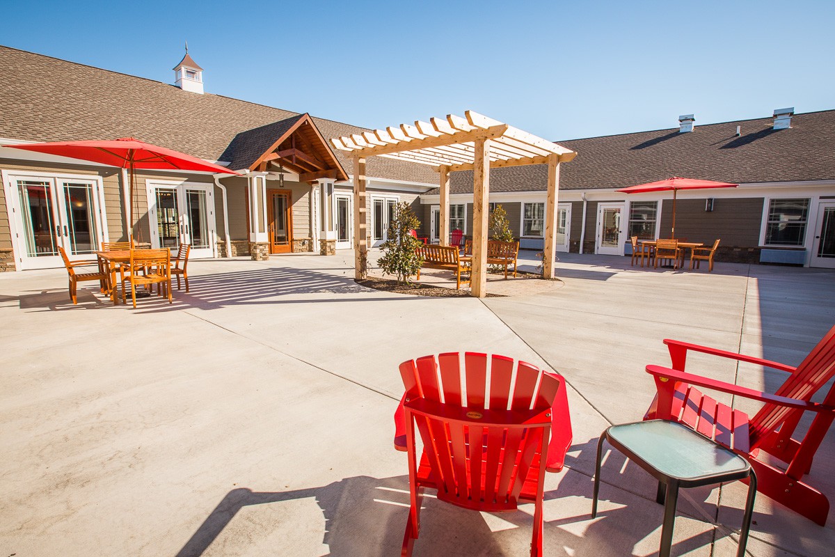 A sunny courtyard with a pergola and colorful outdoor seating.