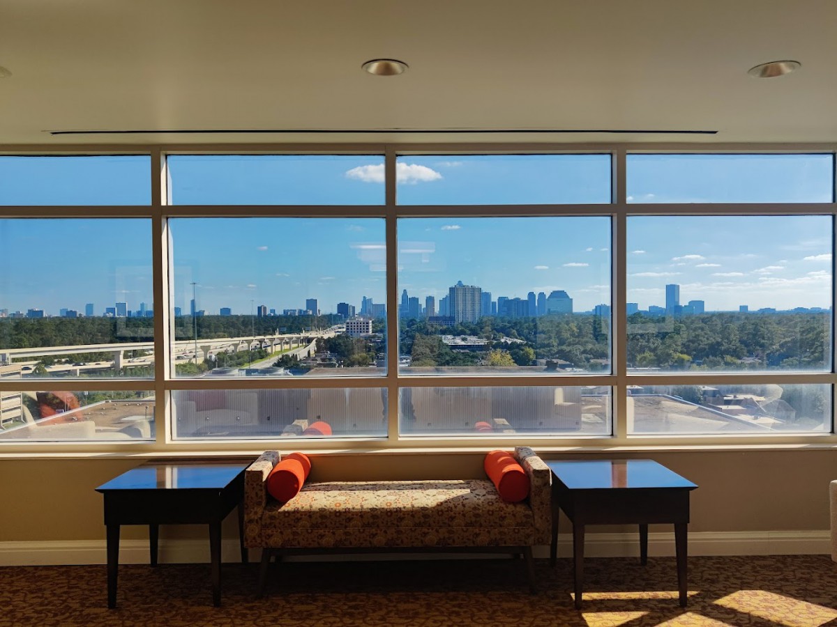 A spacious room with large windows overlooking a city skyline.
