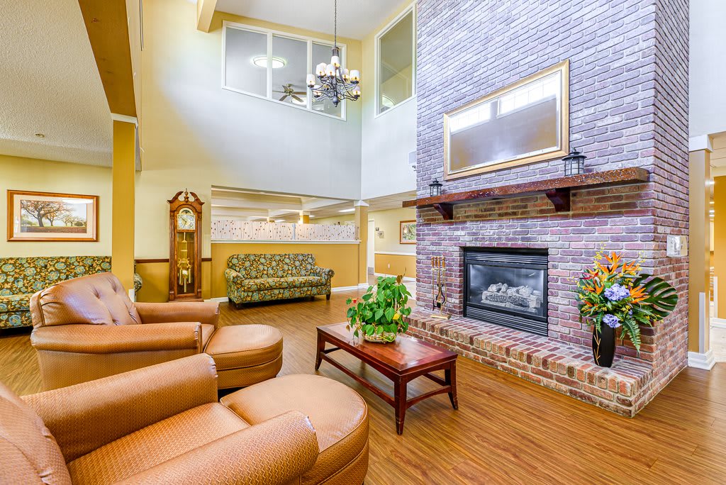 A cozy living room featuring a brick fireplace, comfortable seating, and a classic grandfather clock.