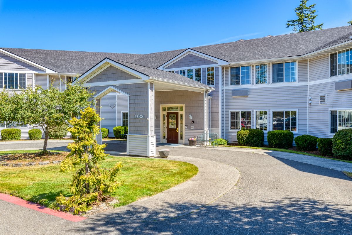 A residential-style building with a driveway and landscaped surroundings.