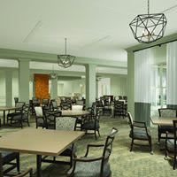 A modern dining room interior featuring multiple tables and chairs with stylish lighting fixtures.