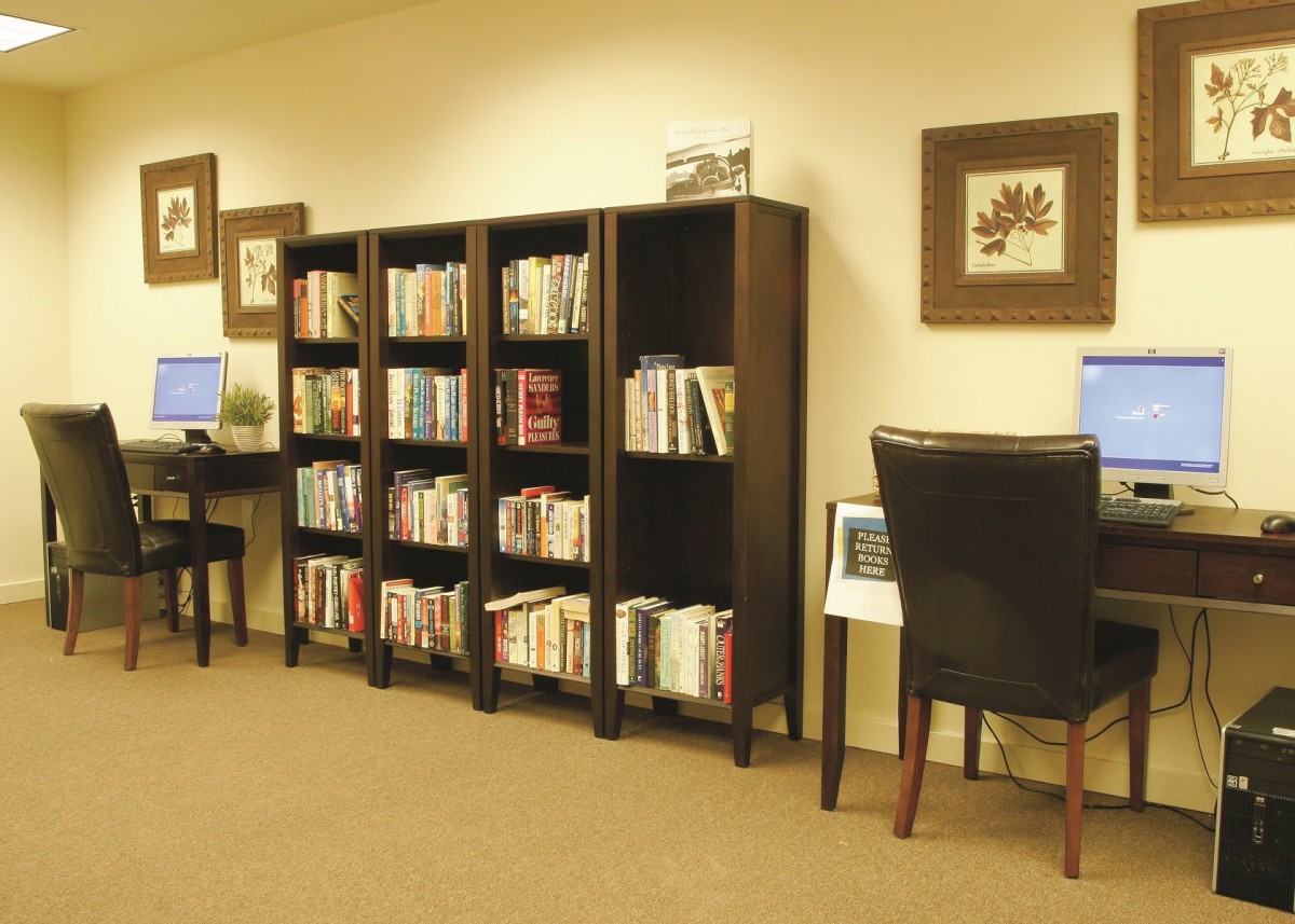 A cozy library corner featuring bookshelves and computer workstations.