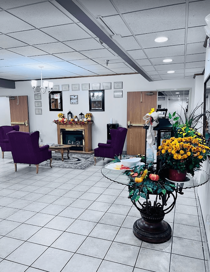 A cozy lobby area with purple chairs, floral decorations, and a central table.