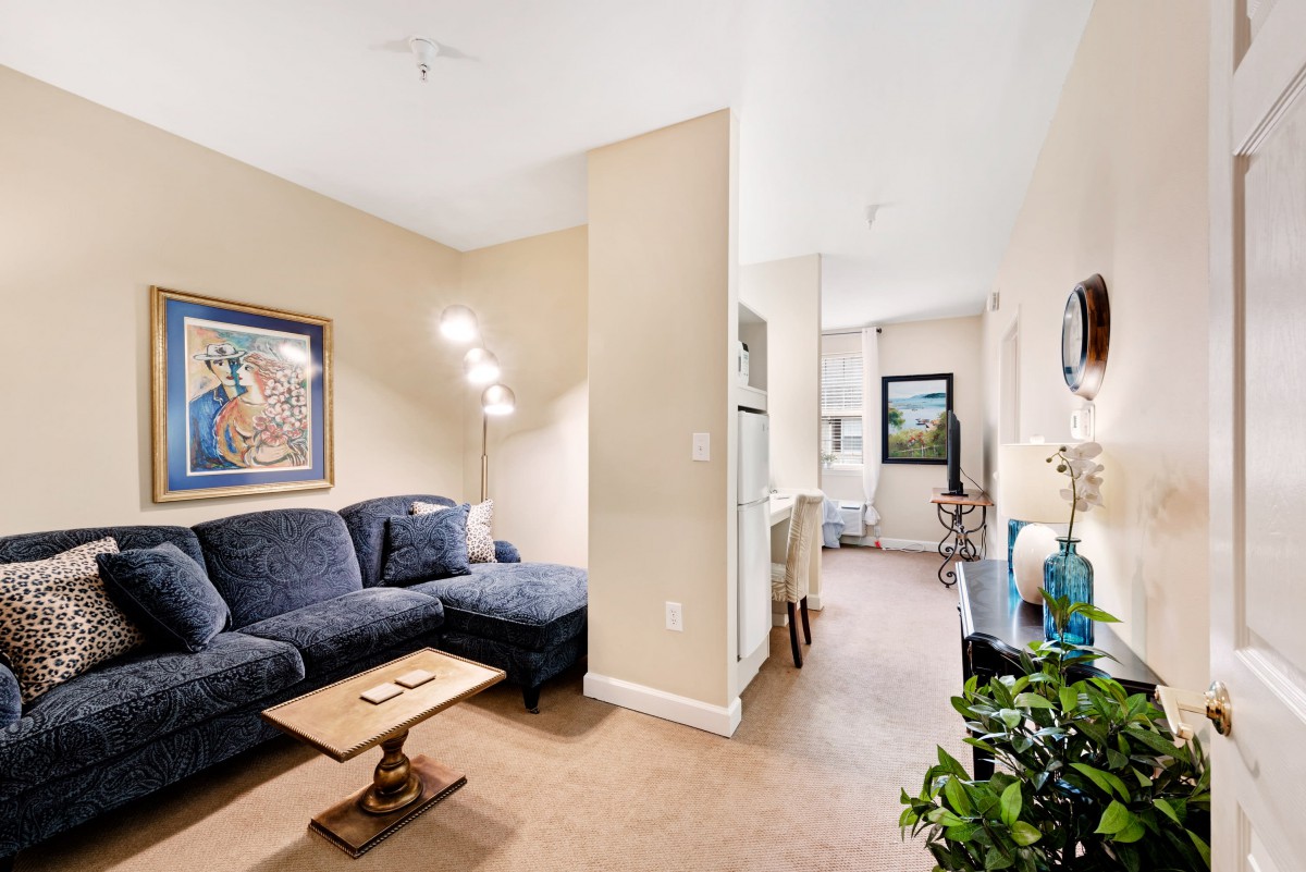 A cozy living room featuring a dark blue sofa, artwork on the wall, and a stylish floor lamp.
