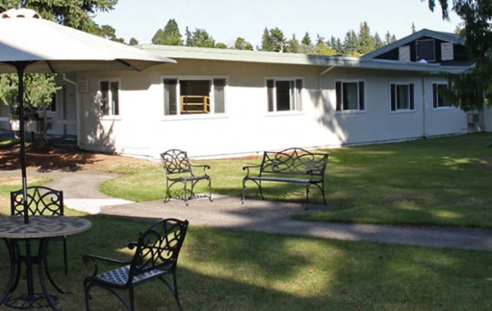 A sunny outdoor area with benches and a pathway in front of a building.