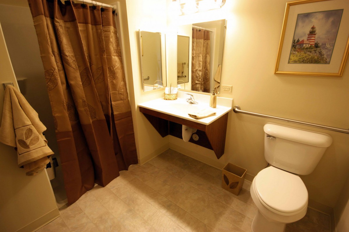 A well-lit bathroom with a mirror, sink, and toilet.