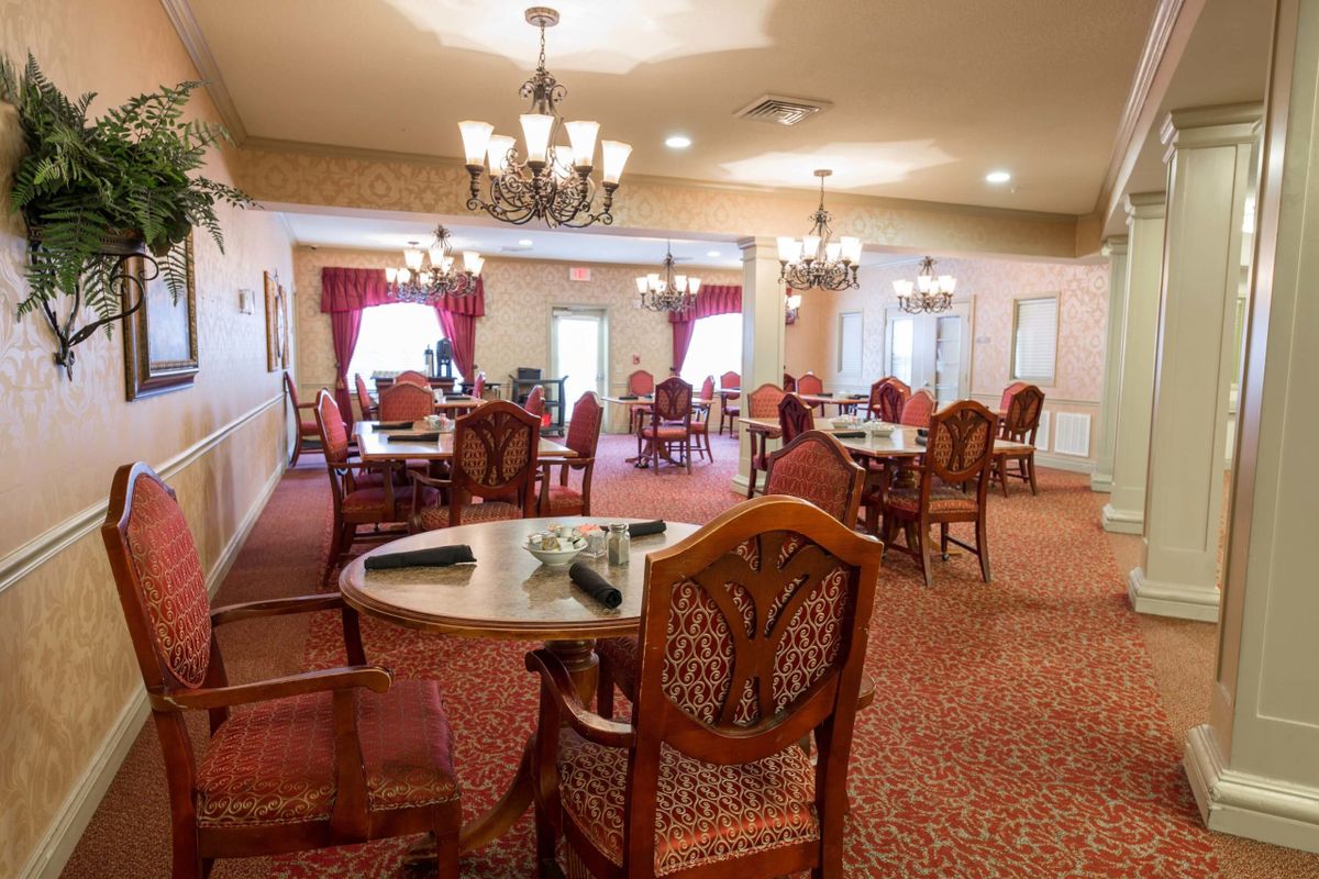 A spacious dining room with elegant wooden furniture and chandeliers.