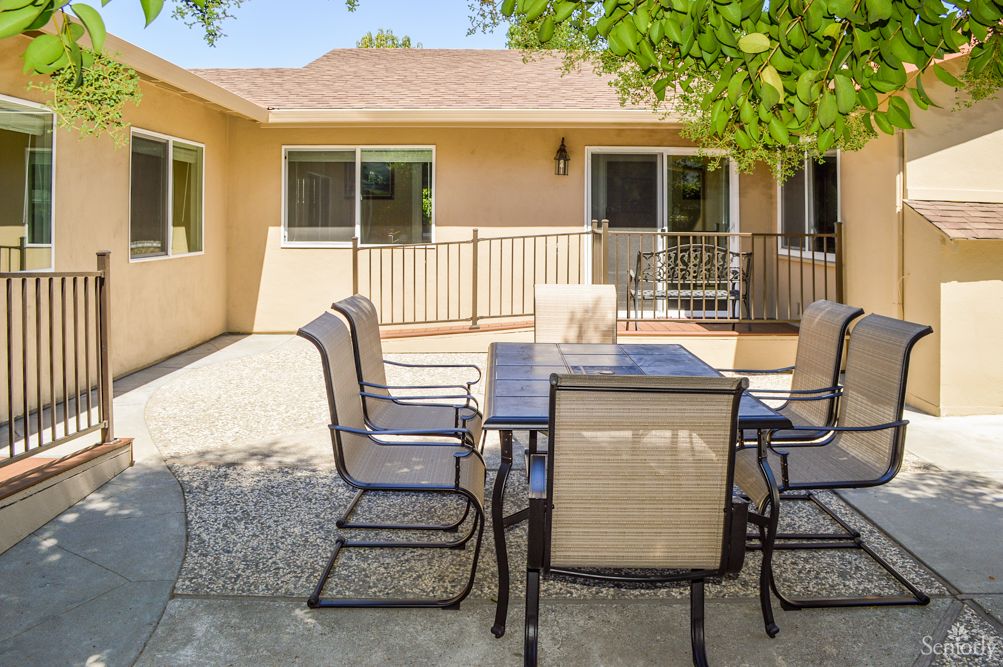 A sunny backyard patio area with a table and chairs.