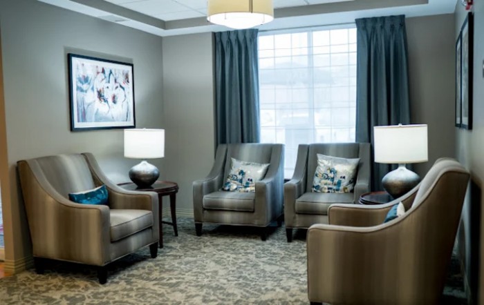 A cozy living room with several armchairs arranged around a central table, complemented by elegant lamps and curtains.