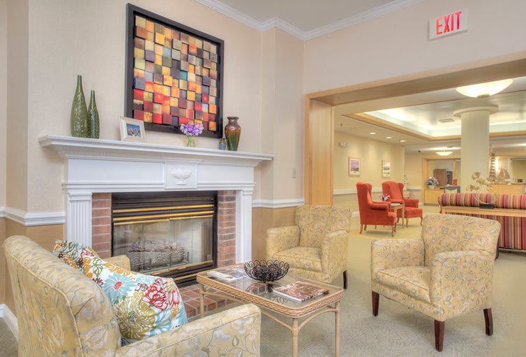 A cozy living room with a fireplace, comfortable seating, and colorful artwork on the wall.