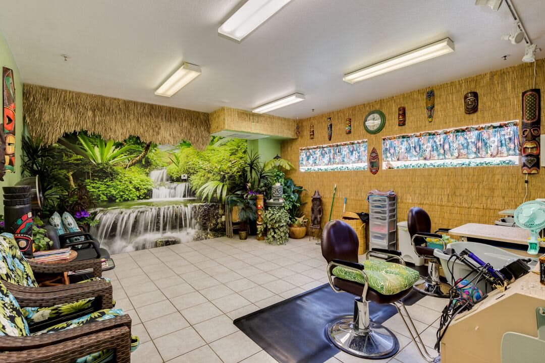 A tropical-themed hair salon with lush indoor plants and a waterfall feature.