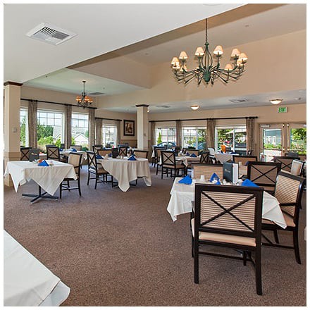 An elegant dining room in a restaurant featuring tables with white tablecloths and a chandelier.