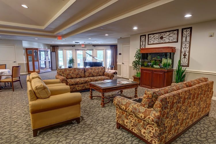 A cozy living room featuring comfortable seating arrangements, a coffee table, a fish tank, and decorative indoor plants.