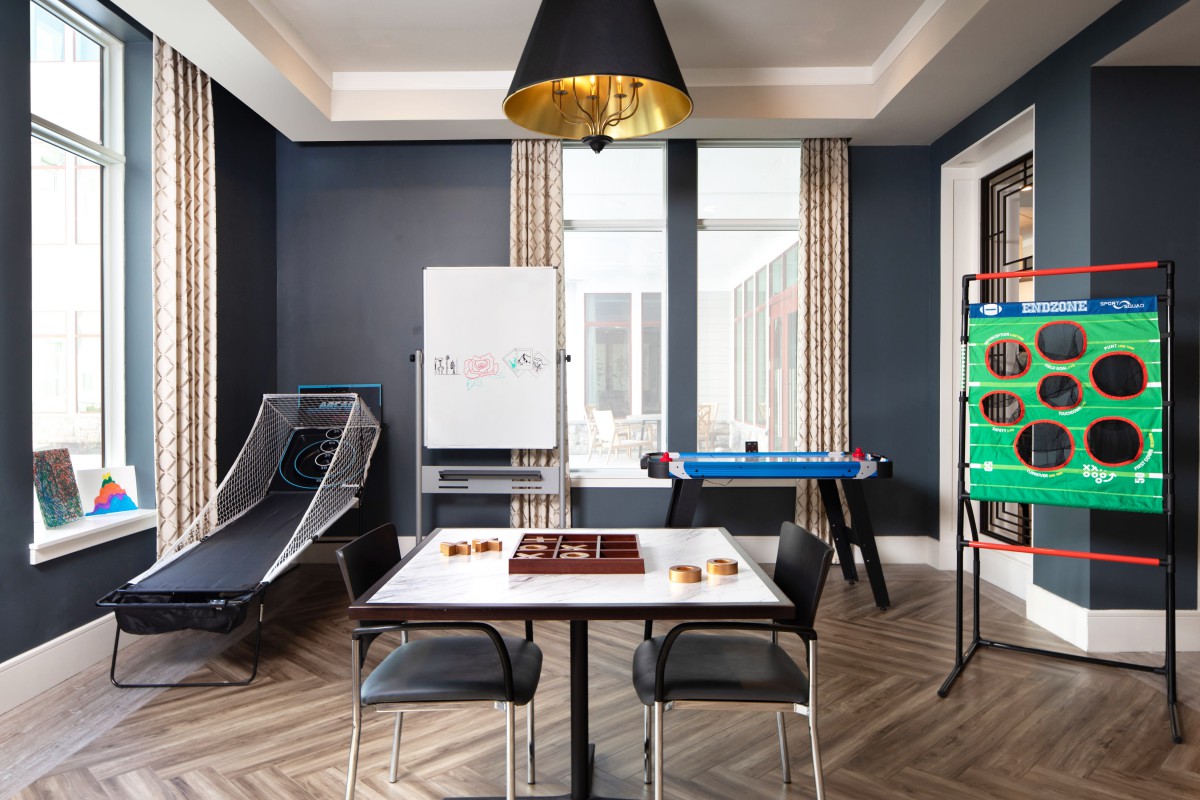 A modern game room featuring a chess board, air hockey table, basketball hoop, and stylish furniture.