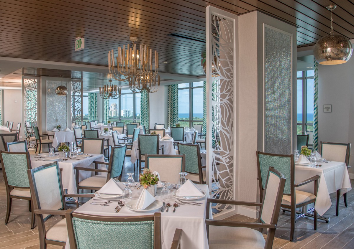 A beautifully set dining area in an elegant restaurant with chandeliers and neatly arranged tables.
