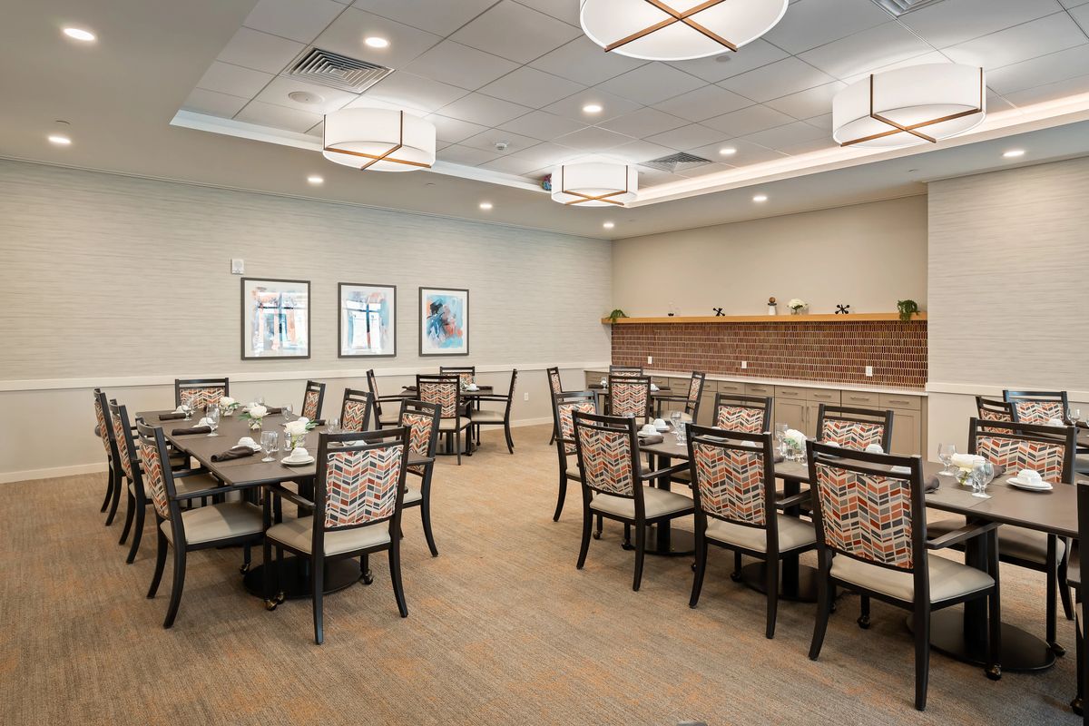 A well-lit dining room with several arranged tables and chairs, featuring elegant interior design.