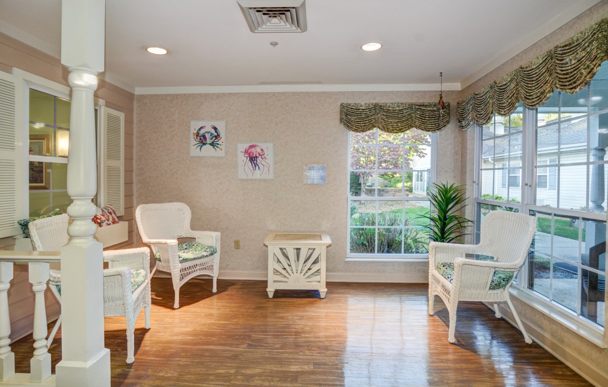 A cozy waiting room with chairs, a small table, and large windows allowing natural light.