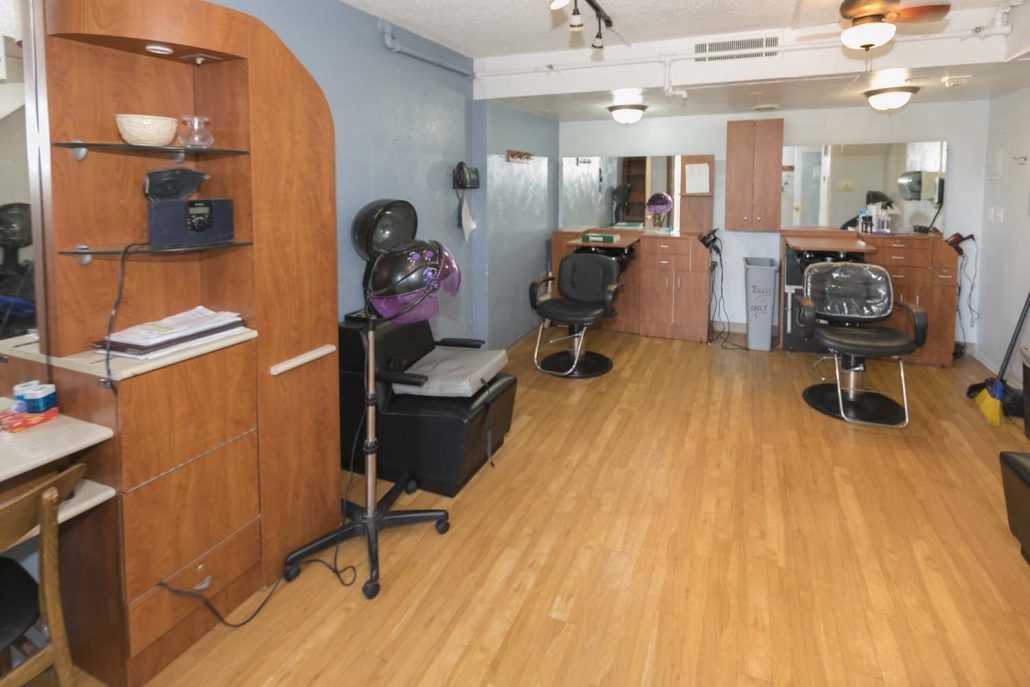 A well-organized hair salon with chairs and mirrors lined up against the walls.
