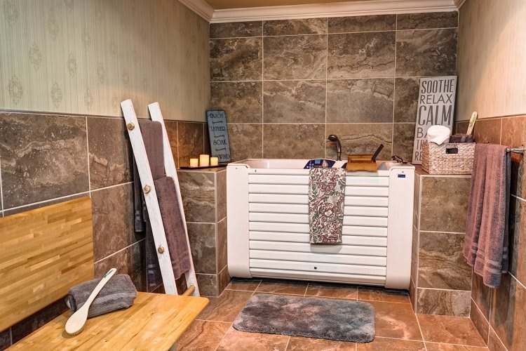 A cozy indoor sauna room with tiled walls, a wooden bench, and neatly arranged towels.