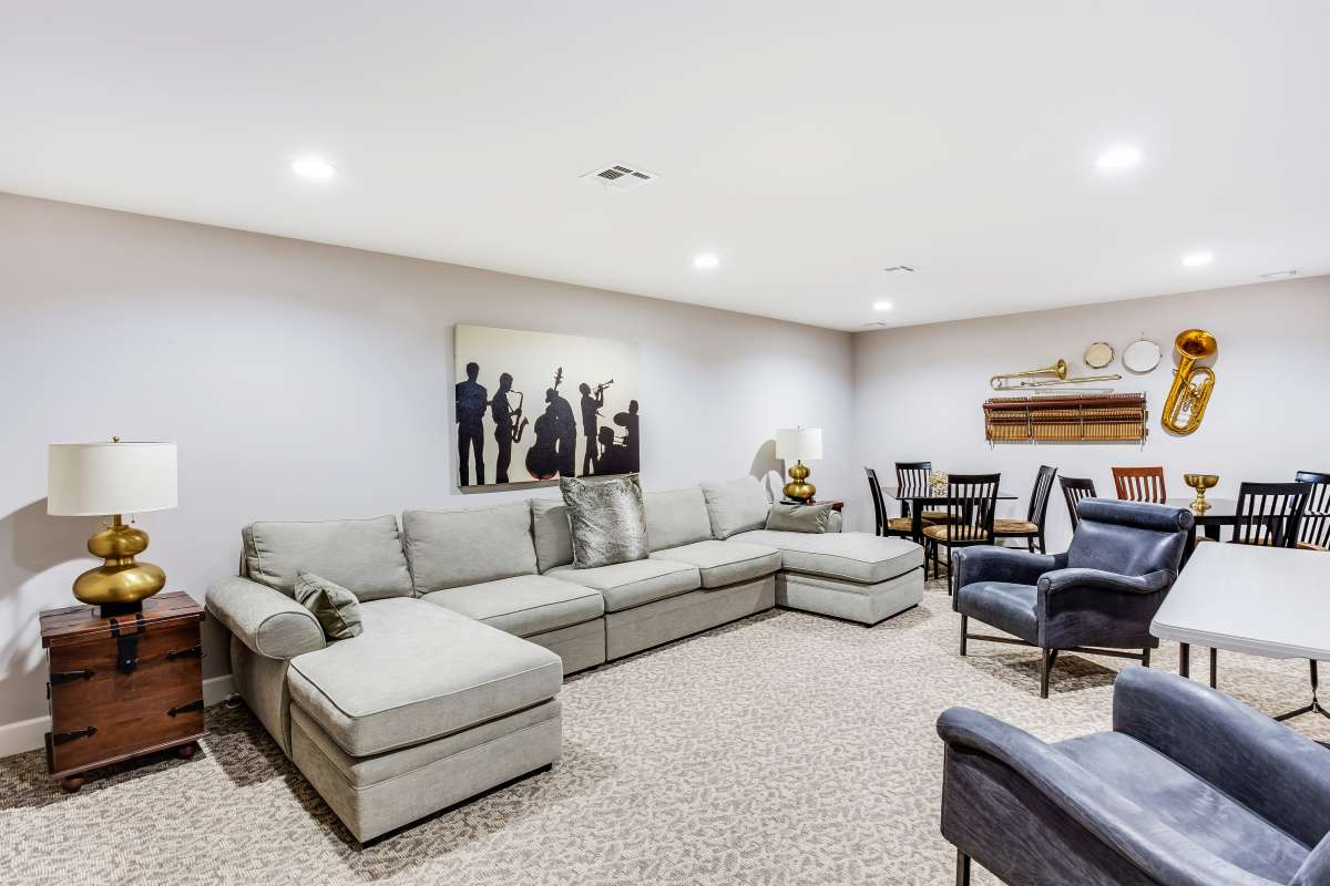 A modern living room featuring a large sectional sofa, accent chairs, and a dining area in the corner.