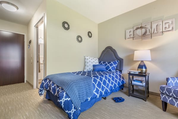 A neatly arranged bedroom featuring a single bed with blue patterned bedding and tasteful decor.