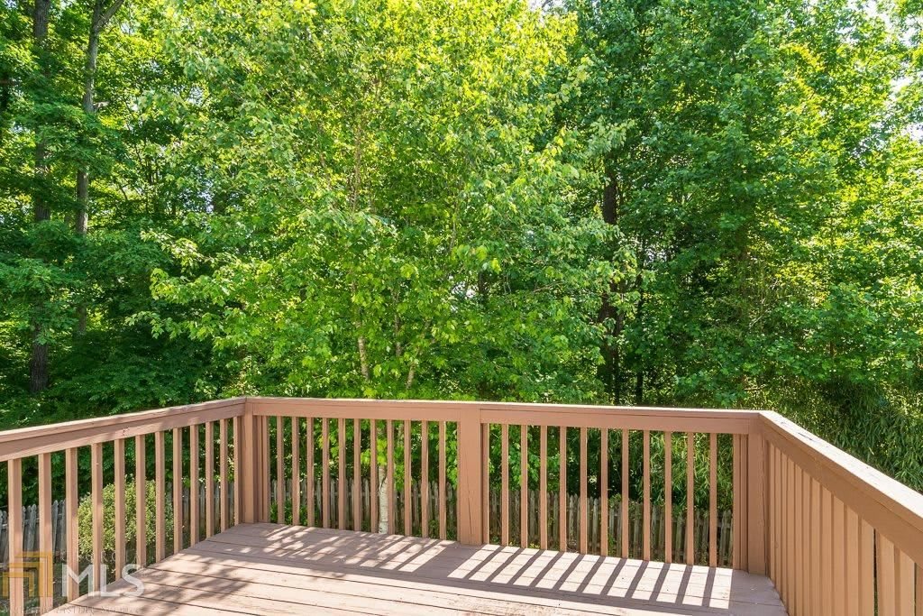 A sunny view from a wooden deck overlooking lush green trees.