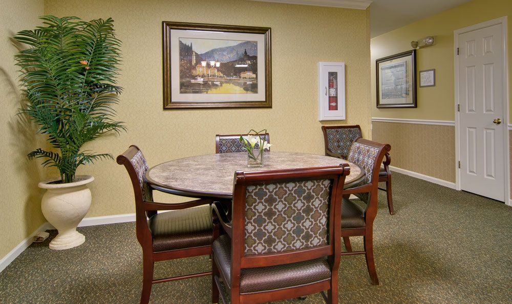 A cozy dining area with a round table, cushioned chairs, and decorative artwork on the walls.