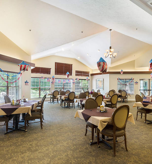 A spacious dining room with neatly arranged tables and chairs, featuring large windows and elegant decor.