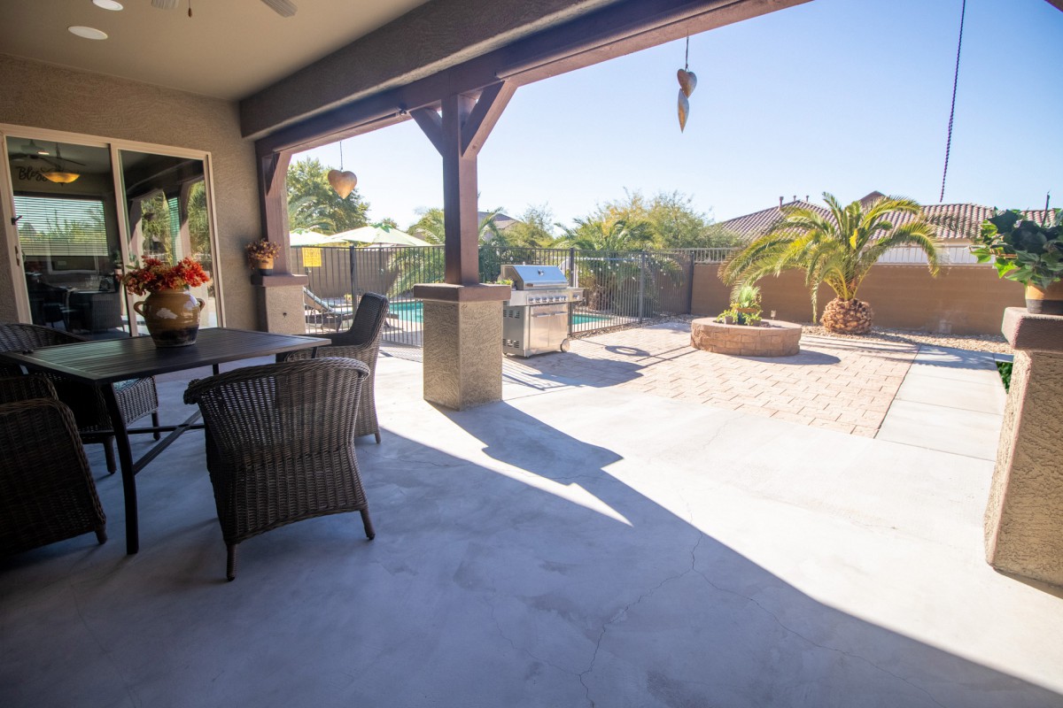 A spacious outdoor patio with furniture overlooking a sunny backyard and pool.
