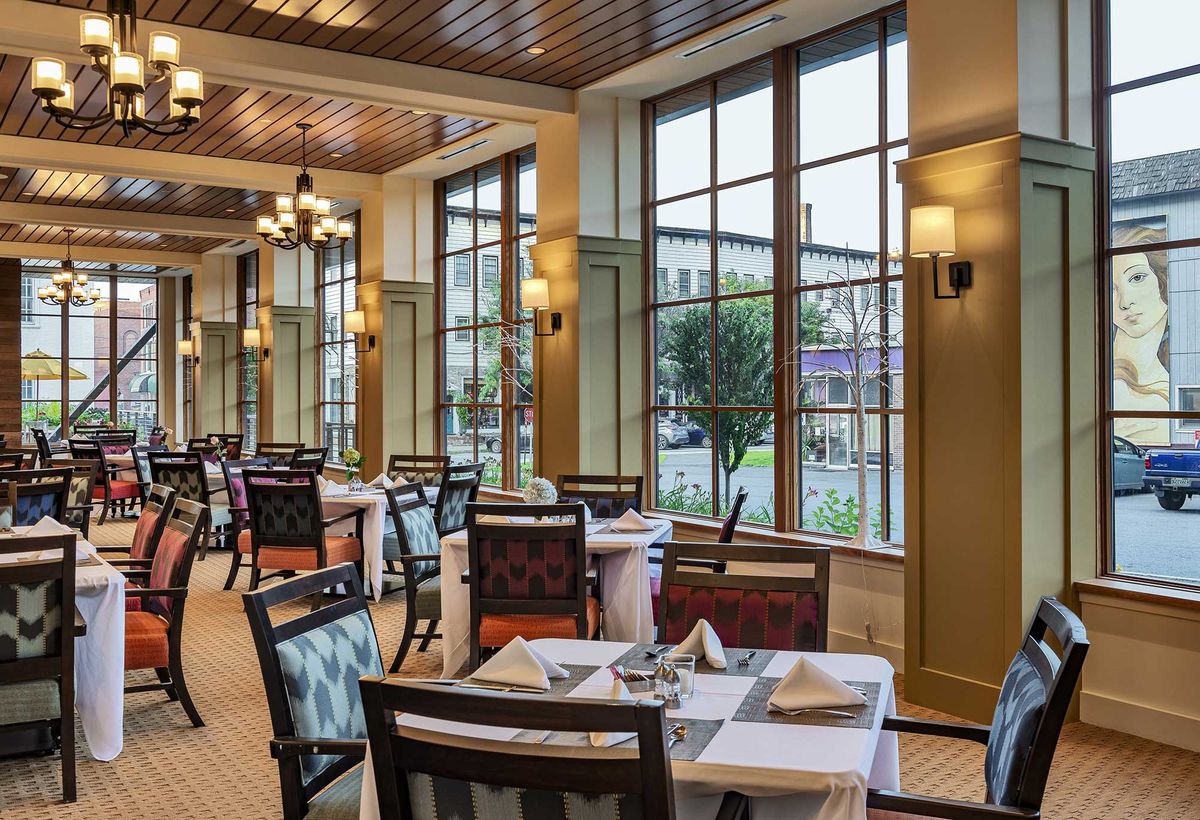 A well-lit restaurant dining area with neatly arranged tables and large windows.