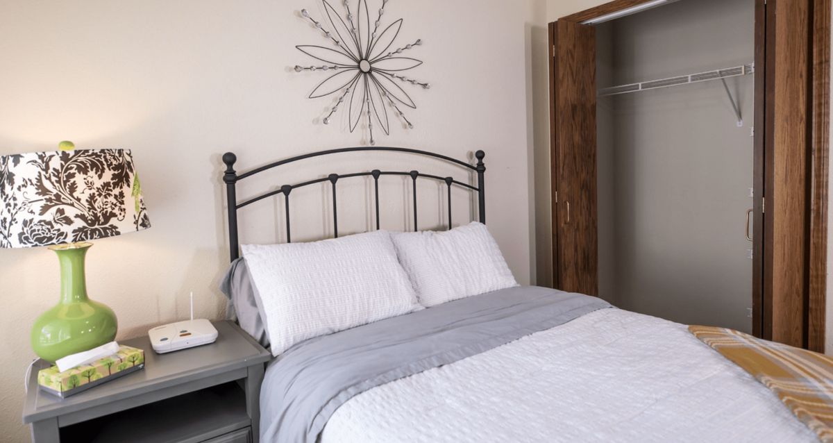 A neatly arranged bedroom with a metal-framed bed and minimalist decor.