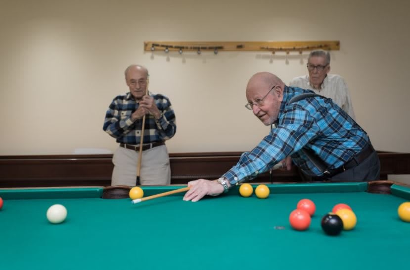 Seniors enjoying a game of billiards indoors.