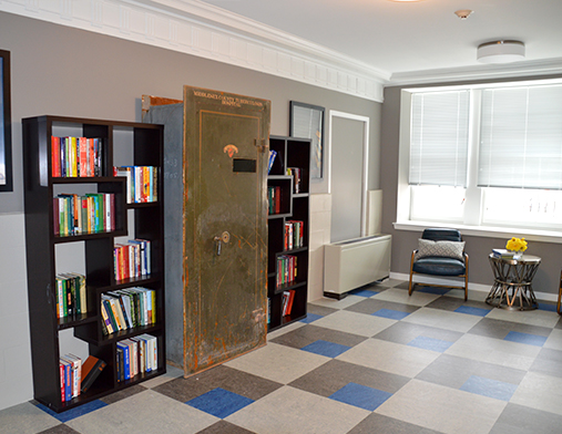 A cozy office space featuring bookshelves filled with books, a large safe, and comfortable seating.