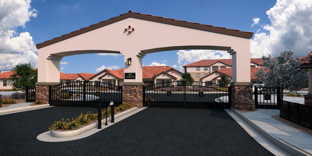 Entrance to a gated residential community with a secure gate and houses in the background.