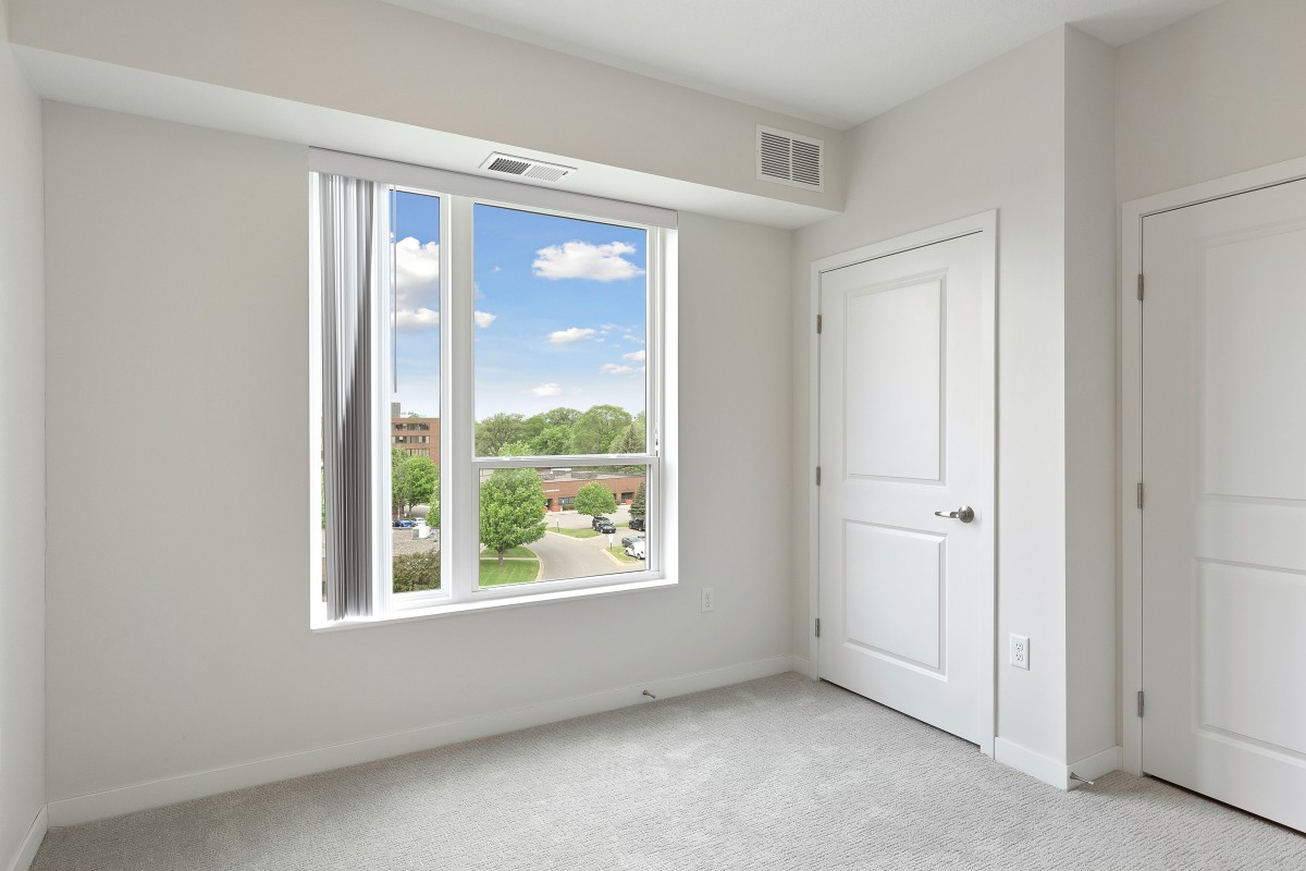 A bright, empty room with a large window and white walls.
