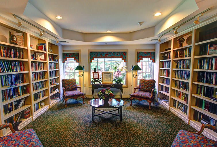 A cozy library reading area with bookshelves, comfortable chairs, and ample natural light.
