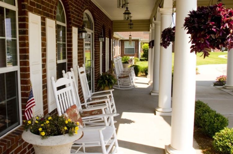 A charming porch with white rocking chairs and hanging plants.
