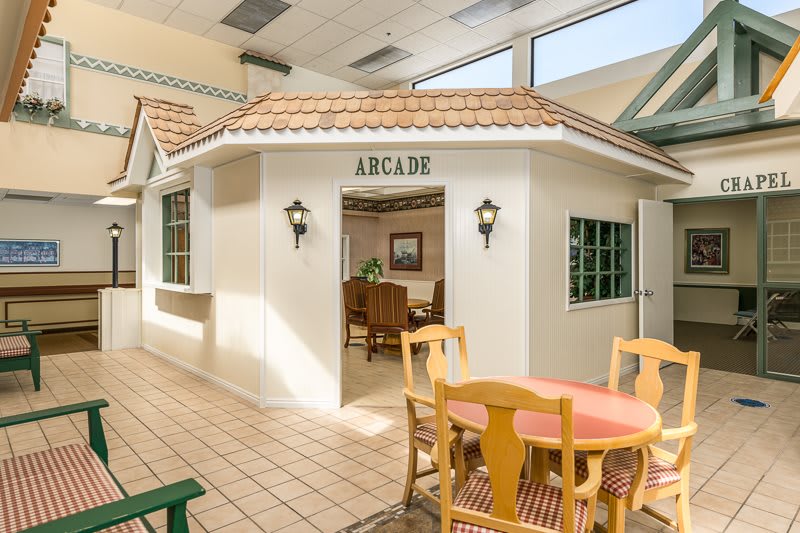 Indoor arcade area with seating and decorative house-like structure.