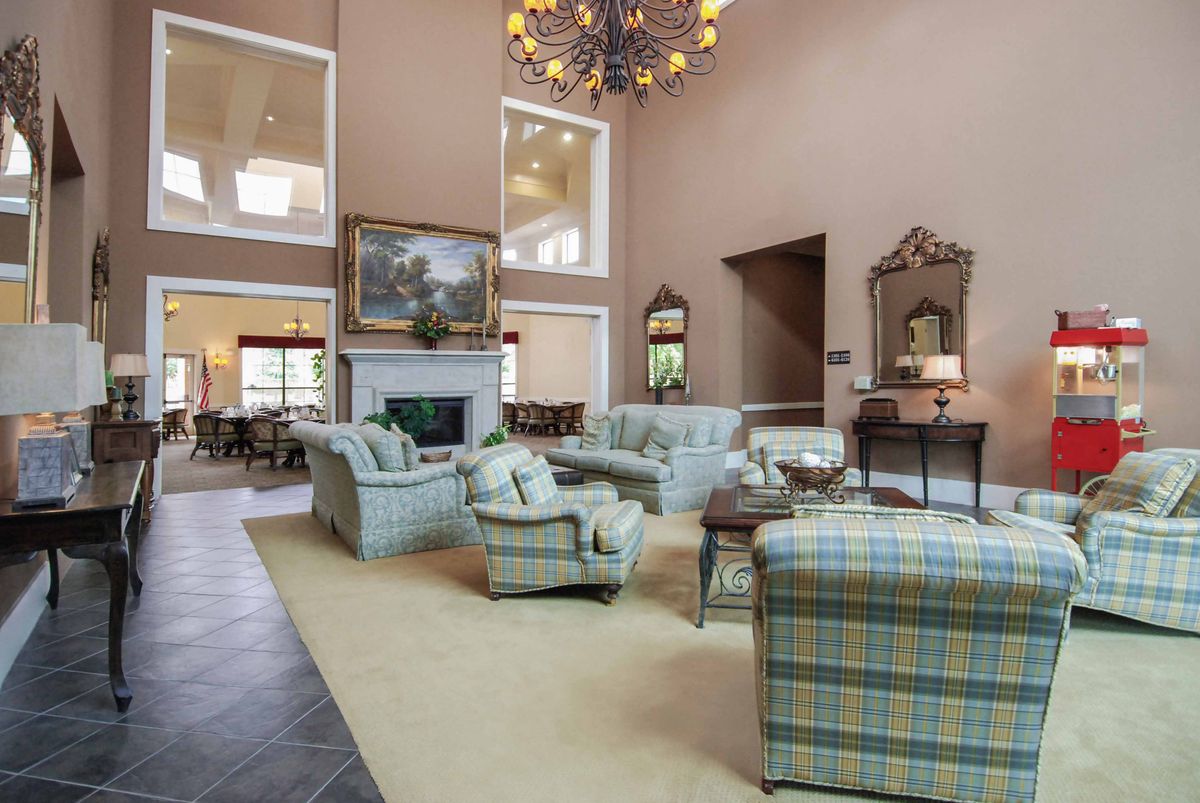 A spacious, elegantly decorated living room with plush seating, a fireplace, and a large chandelier.