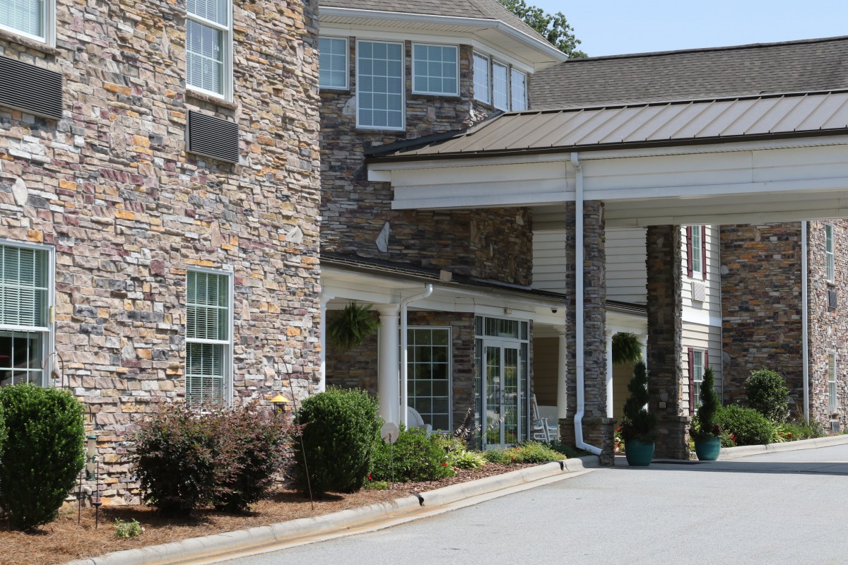 A large building with a stone facade and spacious entryway, surrounded by well-maintained landscaping.